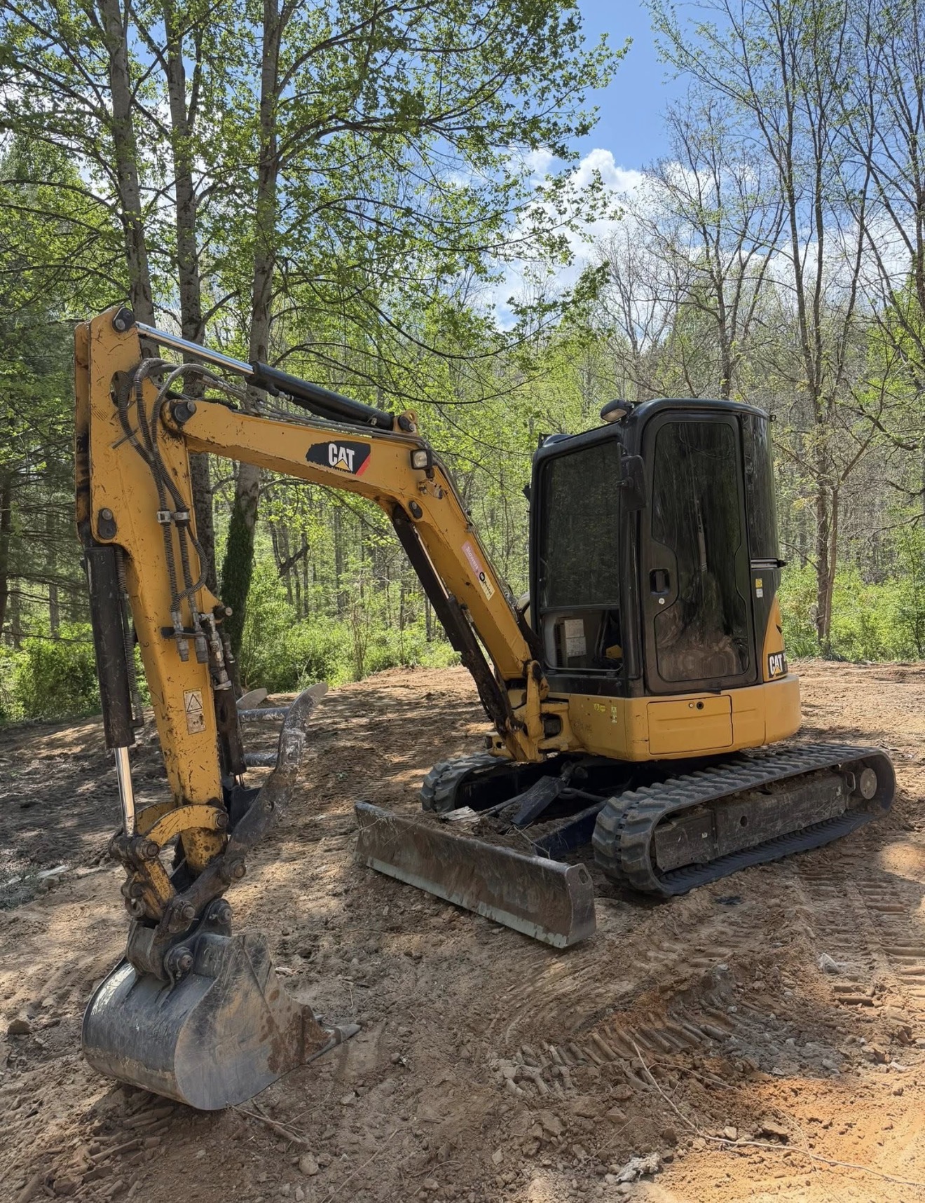Precision Excavation equipment on a wooded job site